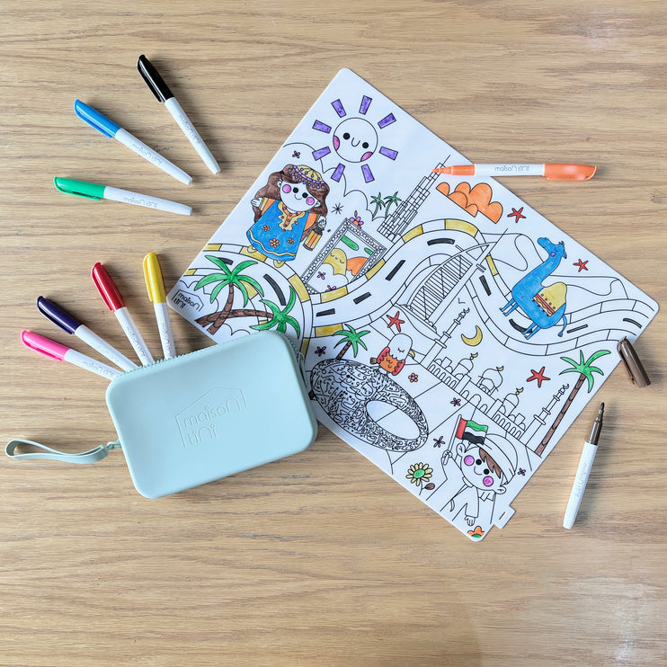 Lifestyle shot of UAE Silicone coloring placemat, partially colored, with all the 9 markers and the silicone pouch to pack them to go. 