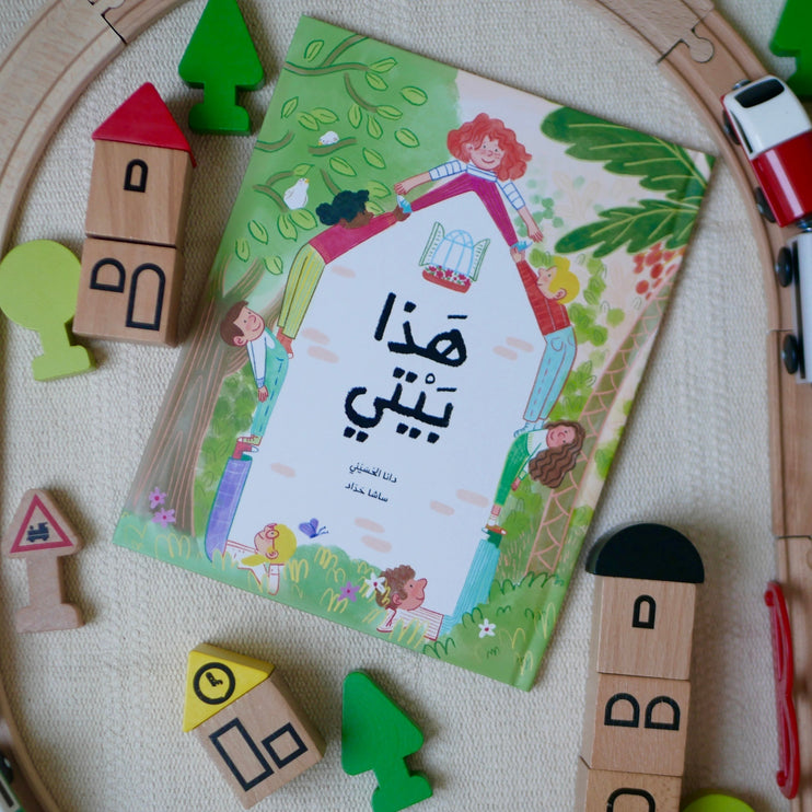 This is My Home book in Arabic on the playmat surrounded by kids wooded toys