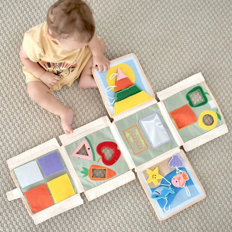 baby playing with the pyramid busy book