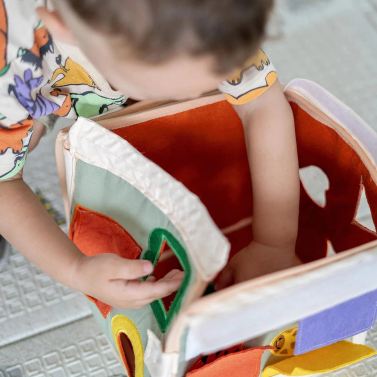 toddler squeezing things in an assembled pyramid busy book