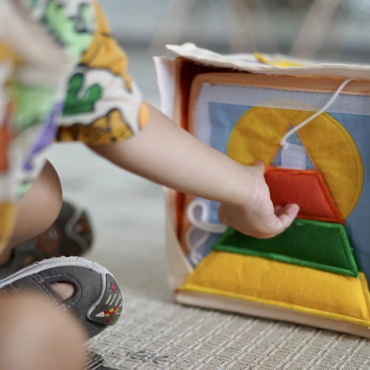 toddler playing with a cube-assembled pyramid busy book